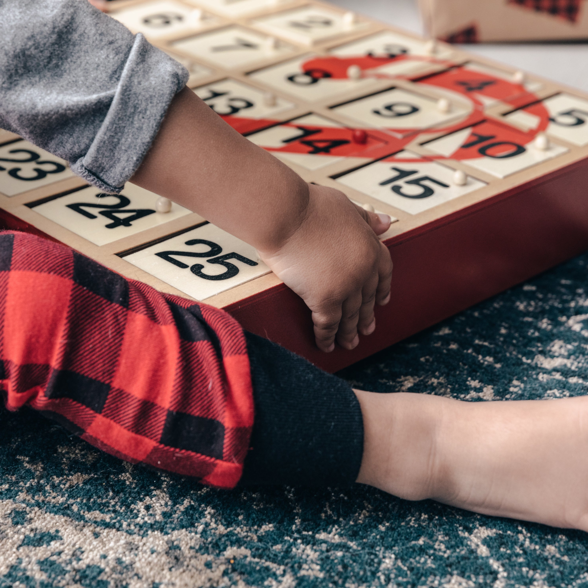 Child playing with a wooden toy with numbers on a carpeted floor